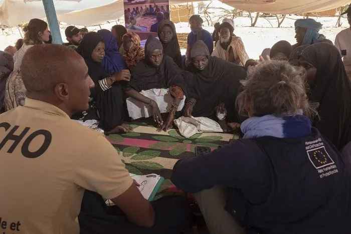 Miembros de la Dirección General de Protección Civil y Operaciones de Ayuda Humanitaria de la Unión Europea (ECHO) participan en una sesión de apoyo psicosocial con mujeres refugiadas fulani que han huido recientemente de Malí, en Fassale, el 5 de noviembre de 2025. Frente al puesto fronterizo de Fassale, en el terreno desértico que separa Malí de Mauritania, unas pocas docenas de personas esperan sentadas en la arena, a la sombra de un muro ocre. Huyen del bloqueo impuesto a su ciudad por los yihadistas del Grupo de Apoyo al Islam y a los Musulmanes (JNIM), afiliado a Al Qaeda, que están reforzando su control sobre el régimen militar maliense, cada vez más debilitado. (Foto de MICHELE CATTANI / AFP) (Foto de MICHELE CATTANI/AFP vía Getty Images)